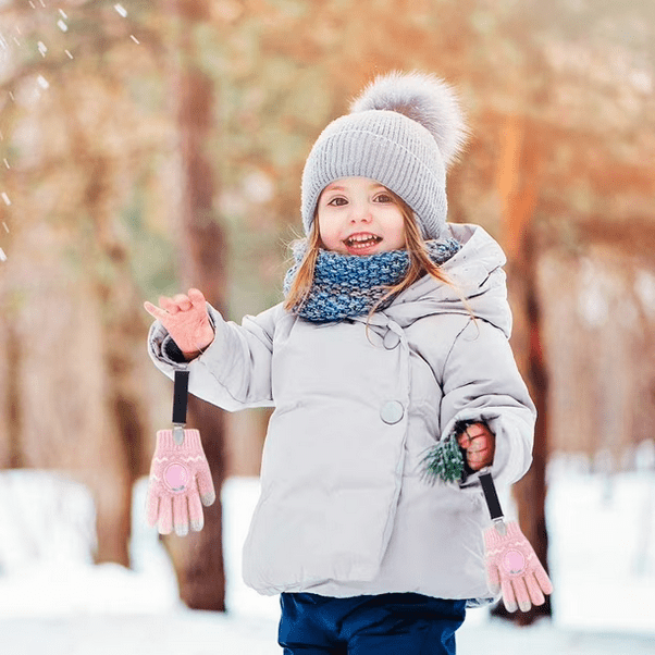 Little girl with gray winter coat and black mitten clips in the snow. Little Gift Nook