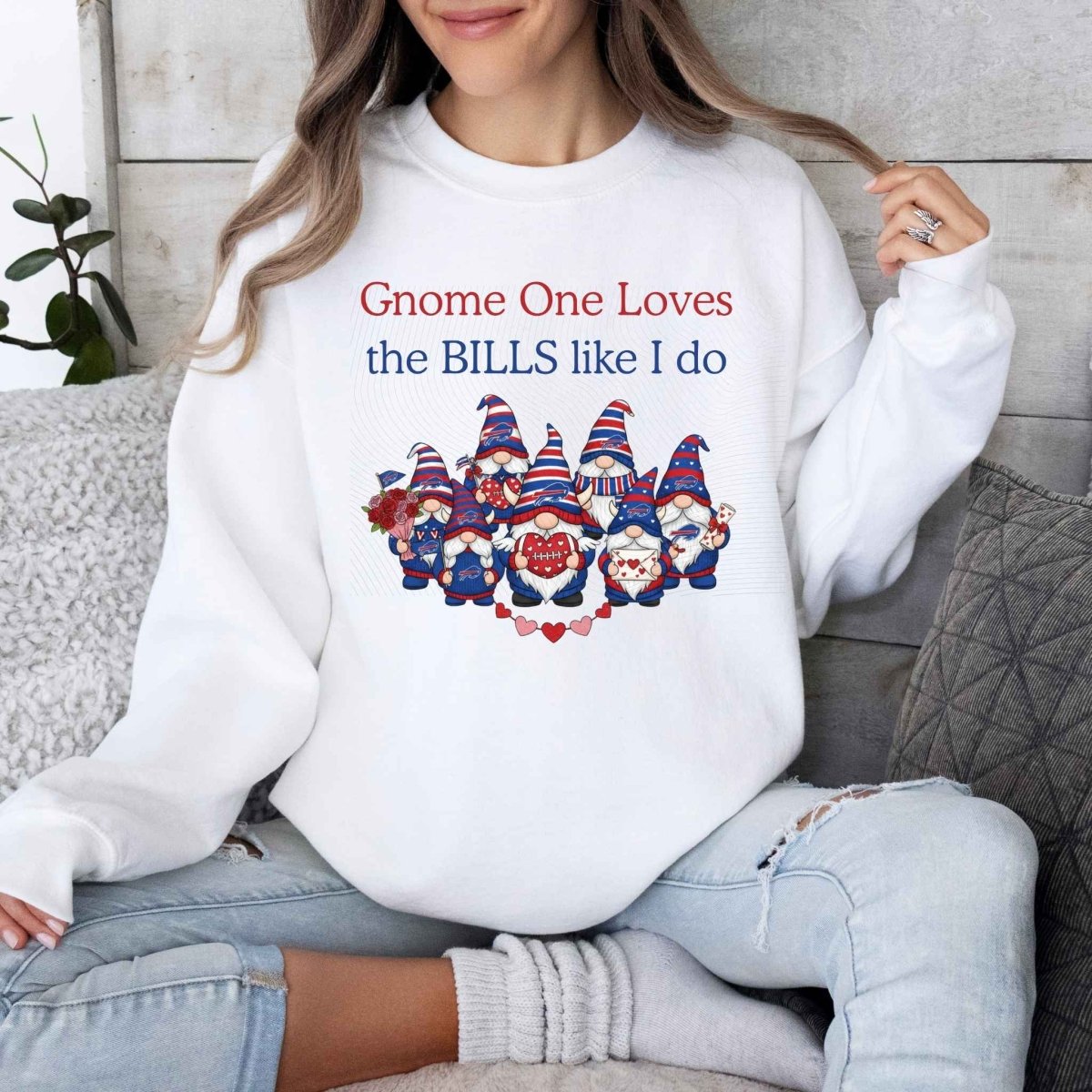 Woman wearing white sweatshirt with red blue gnomes with hearts and caption "Gnome one loves the Bills like I do" buffalo football on front on a wood panel background. Little Gift Nook