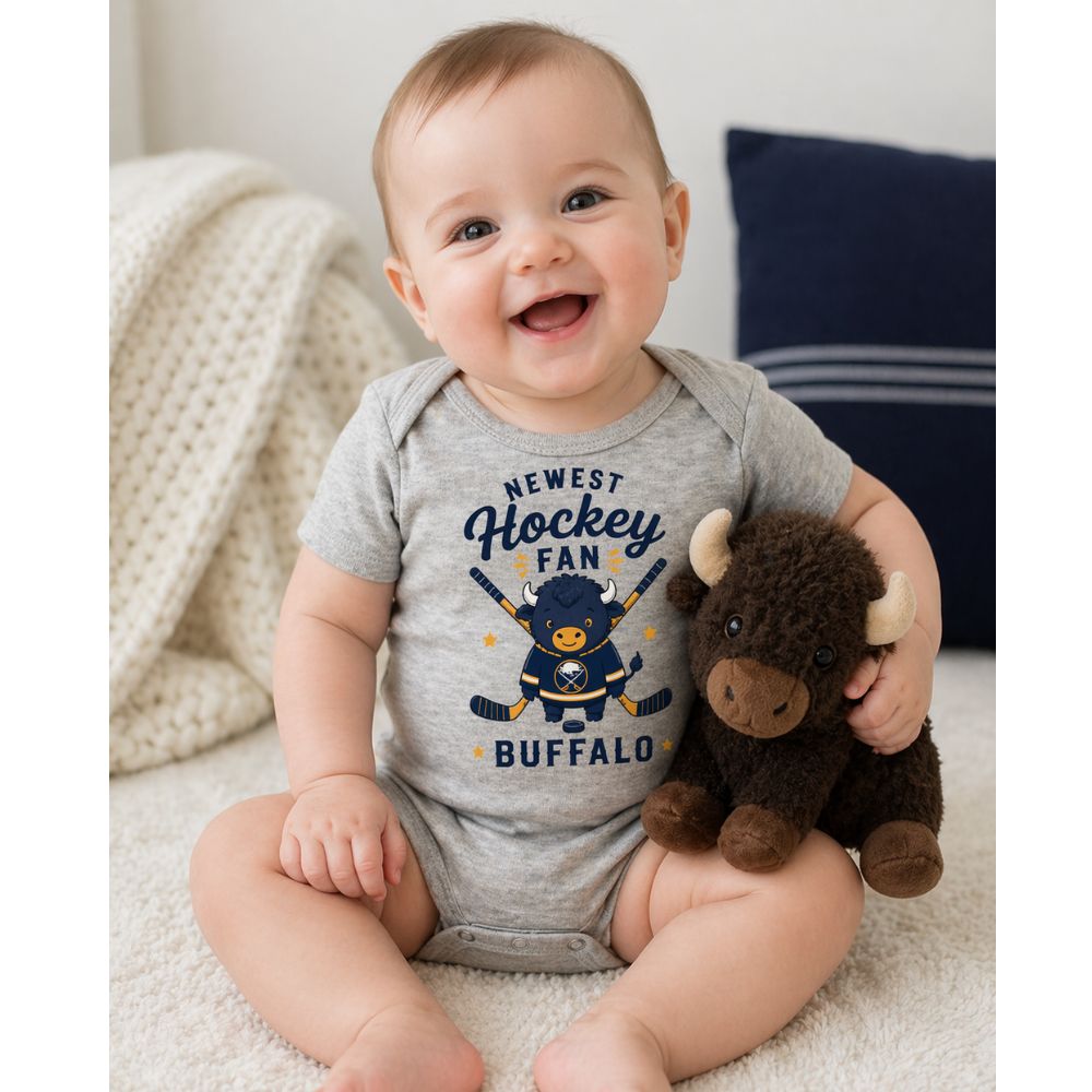 Baby wearing a gray 'Newest Hockey Fan Buffalo' onesie holding a stuffed buffalo toy.