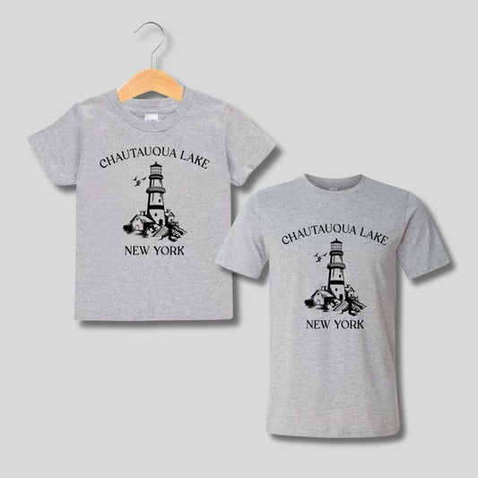 Two gray t-shirts with a lighthouse graphic and 'Chautauqua Lake New York' text on a gray background. Kids shirts - Little Gift Nook.