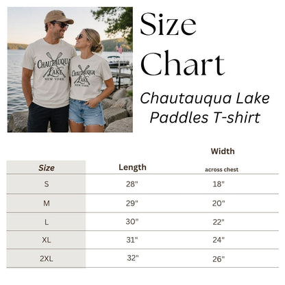 Size chart for beige Chautauqua Lake Paddles T-shirt with a couple wearing the shirt in the background.