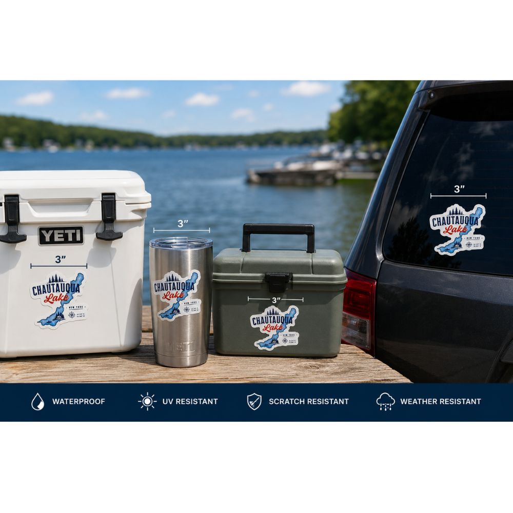 YETI cooler, tumblers, and a cooler with Chautauqua Lake stickers on a wooden surface by a lake.