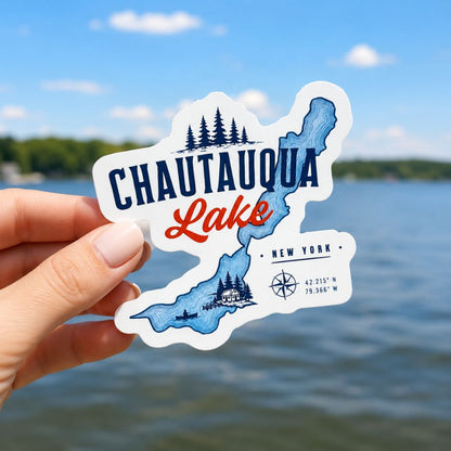 Sticker of Chautauqua Lake, New York held in front of a lake with trees and sky.