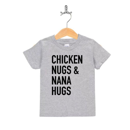 Heather gray kids tshirt with black text on front "Chicken nugs & nana hugs" hanging on wooden hanger on white background.
