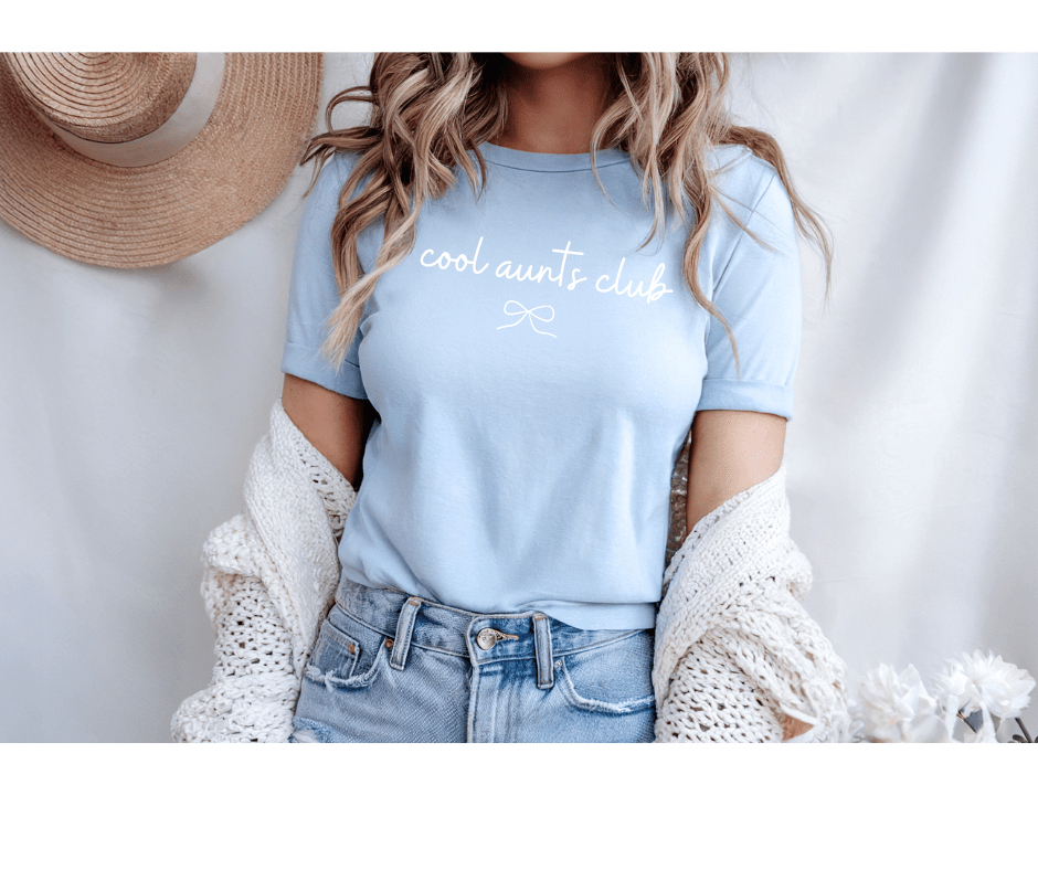 Woman wearing Baby Blue T-Shirt with white bow and Cool Aunts Club on front on a white background. Little Gift Nook