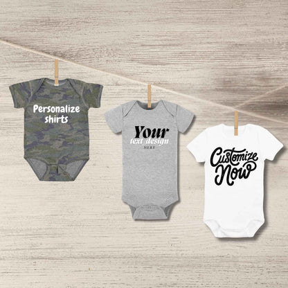 Custom baby onesies in camo, light gray, or white. Personalize baby onesies hanging from clothes pins on a wood background.  Little Gift Nook