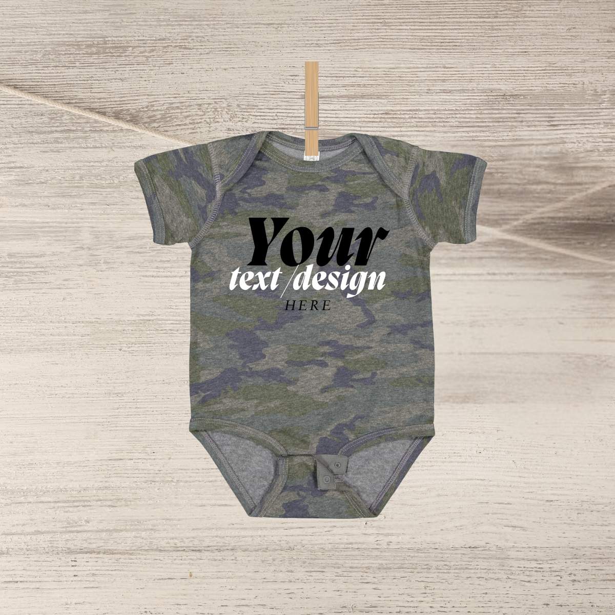 Blank green navy camo baby onesie personalized custom onesie hanging on clothespin n wood background.