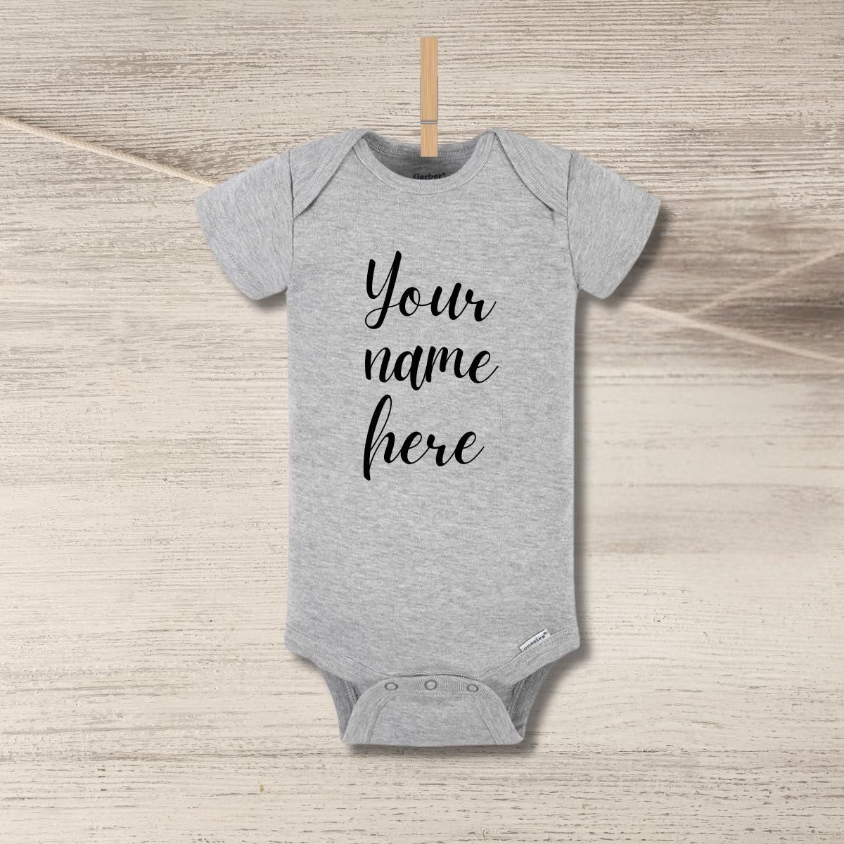 Blank gray baby onesie personalized custom onesie hanging on clothespin n wood background