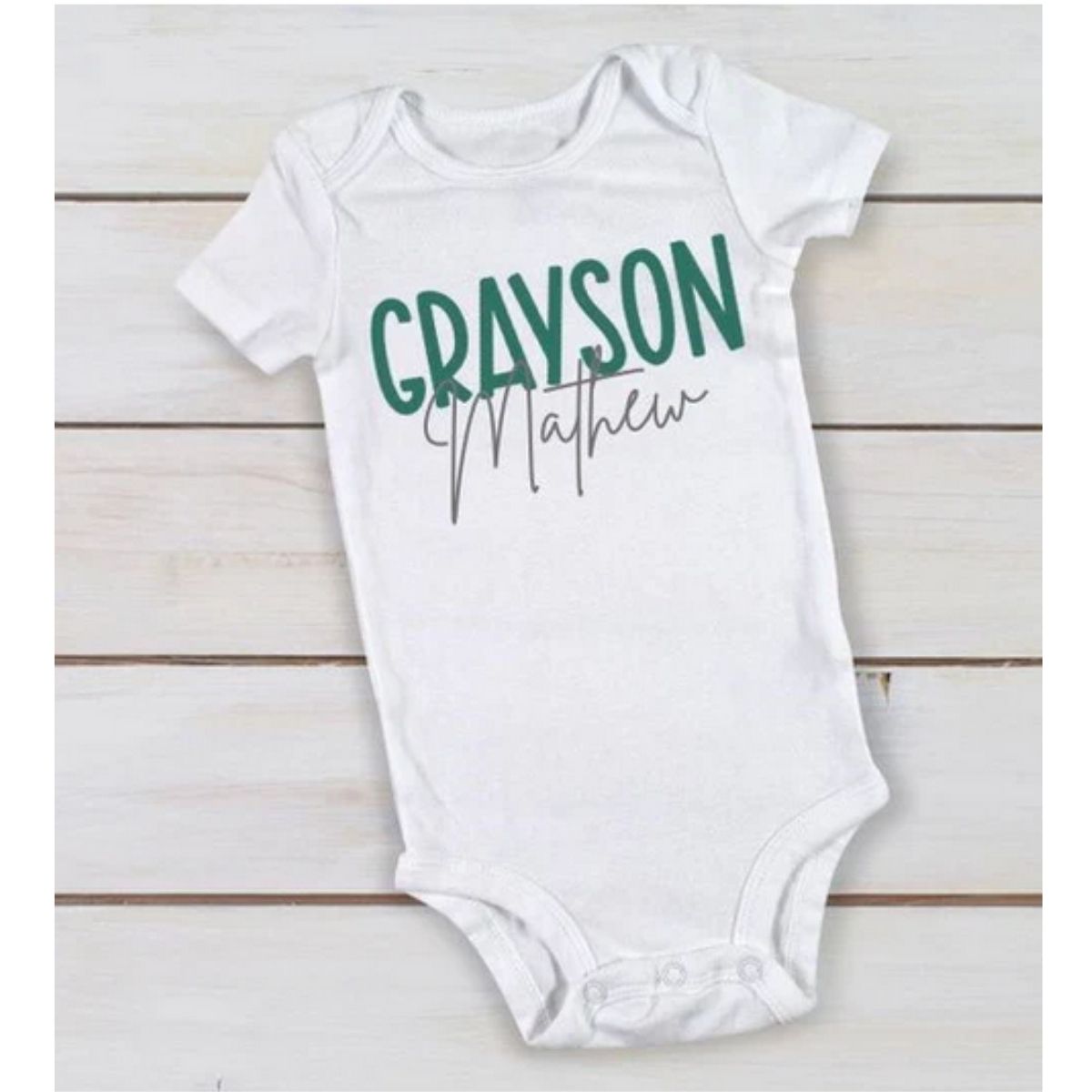 white personalized custom baby onesie with name in green gray on wood background