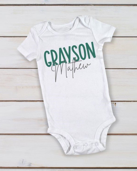 white personalized custom baby onesie with name in green gray on wood background.