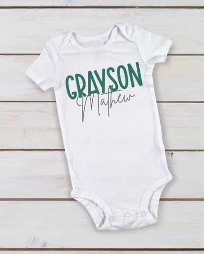white personalized custom baby onesie with name in green gray on wood background.
