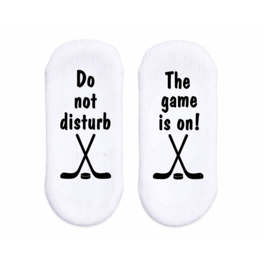 White baby socks with text and hockey stick graphics laying flat on white background.