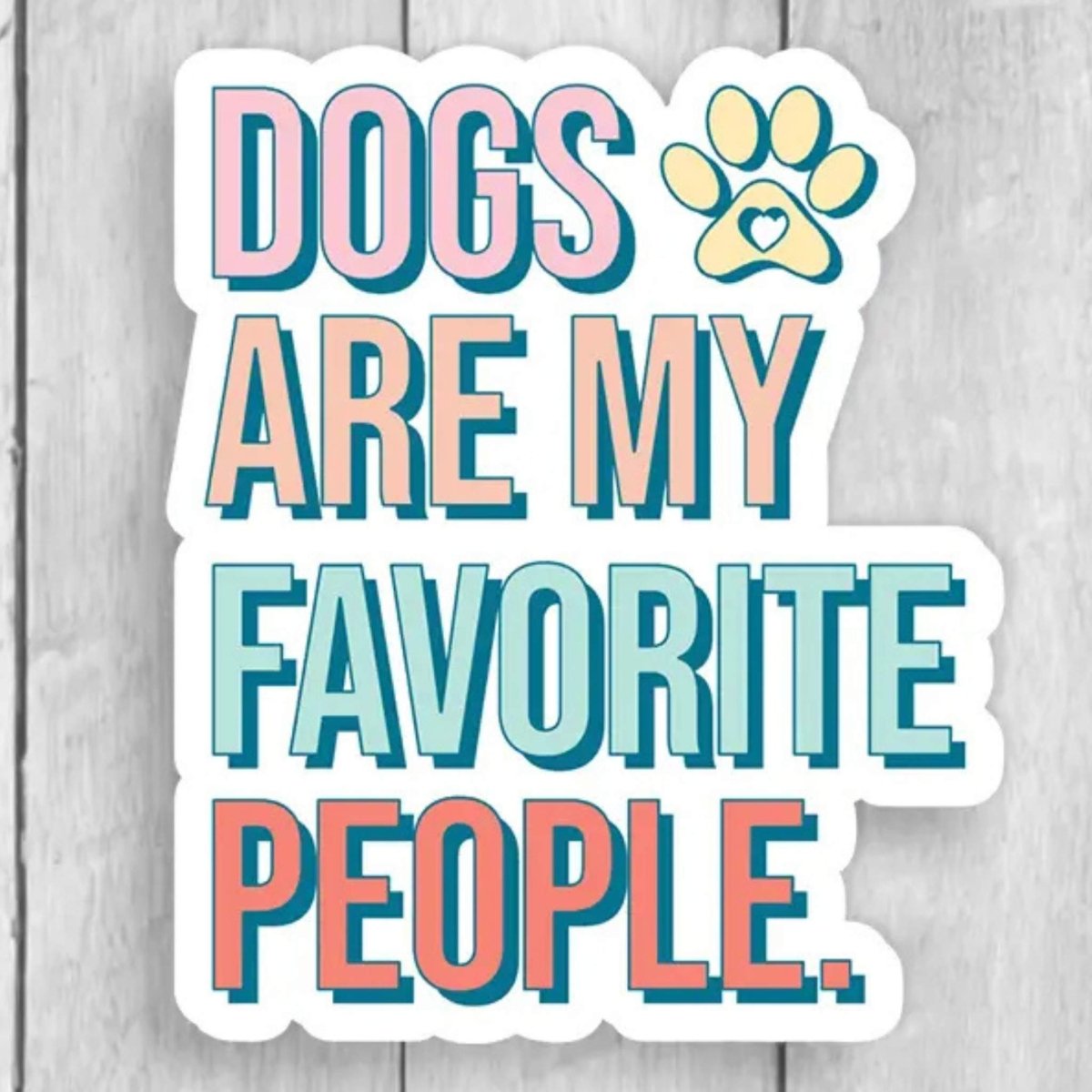 Typography sticker with colorful text "Dogs are my favorite people" on a wood background. Little Gift Nook