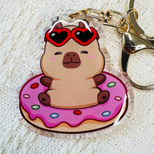 Load image into Gallery viewer, Capybara keychain. Capybara in pink donut pool float with red heart sunglasses. Acrylic, double sided keychain.  Little Gift Nook. 