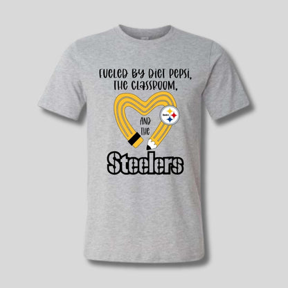 gray tshirt with yellow black pencil heart design and "fueled by diet pepsi, the classroom, and the Steelers" image on front. 