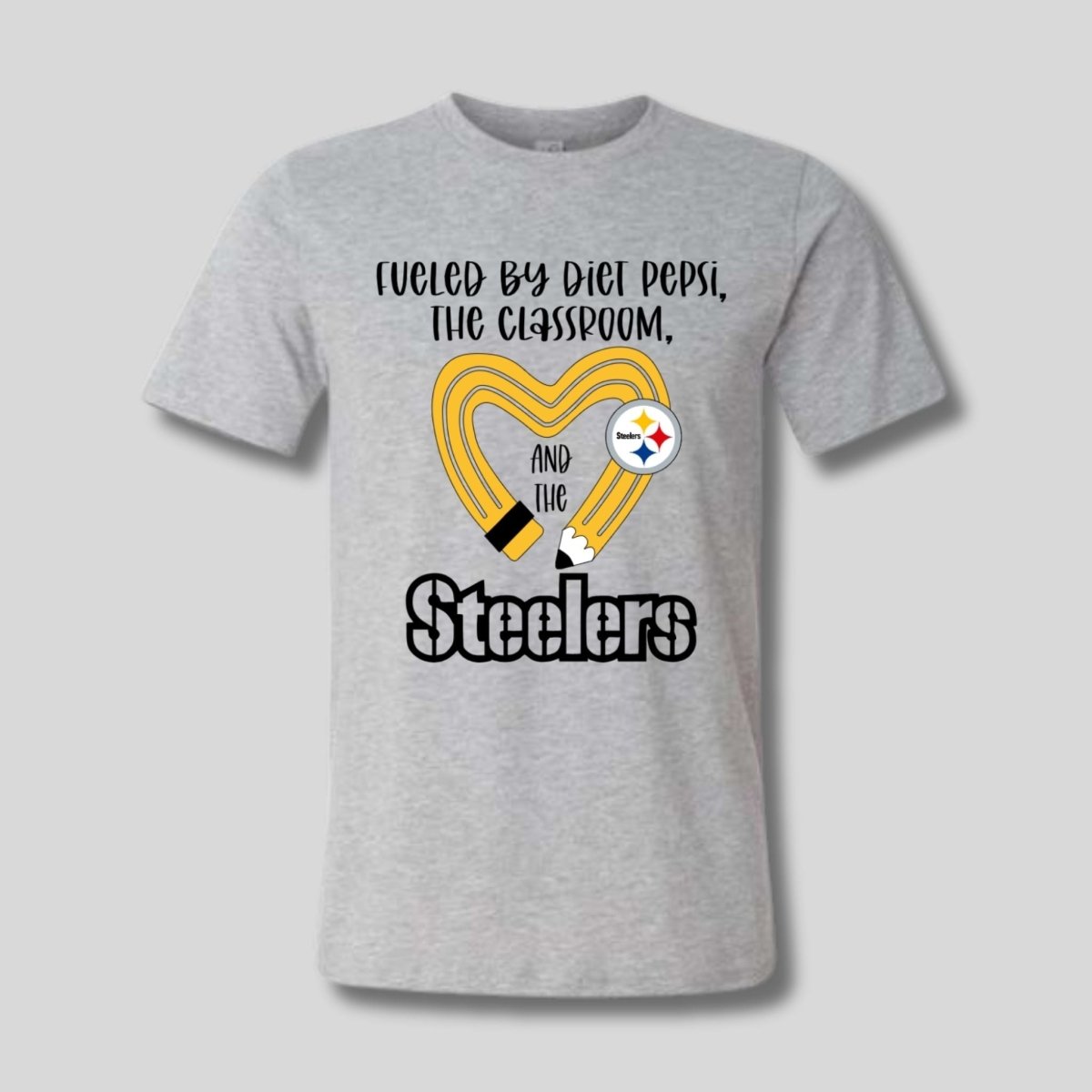 gray tshirt with yellow black pencil heart design and "fueled by diet pepsi, the classroom, and the Steelers" image on front. 