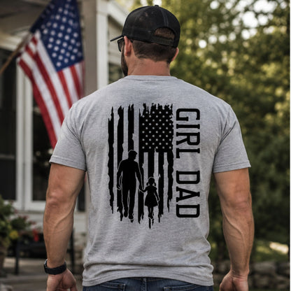 Man wearing heather gray tshirt with GIRL DAD American Flag graphic on back standing outdoors in front of a flag.