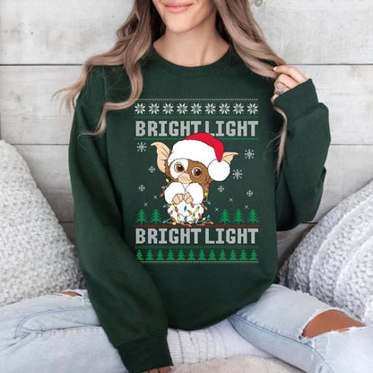 Woman wearing forest green Gizmo Christmas Bright Light sweatshirt sitting on wood background. 