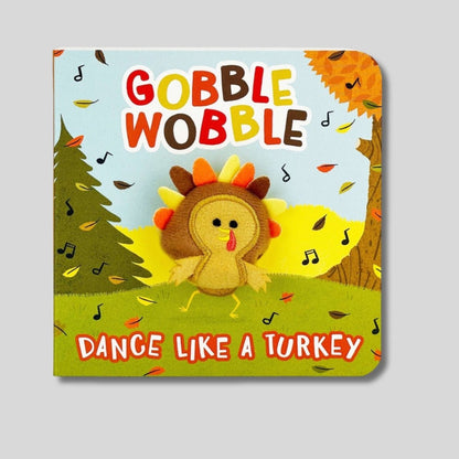 Gobble Gobble Dance like a Turkey mini kids puppet board book with fall scene and little turkey puppet that pops through. Book sitting on gray background. 
