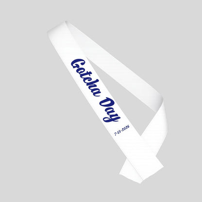 White sash with blue "Gotcha Day" and date sash for adoption on a gray background.