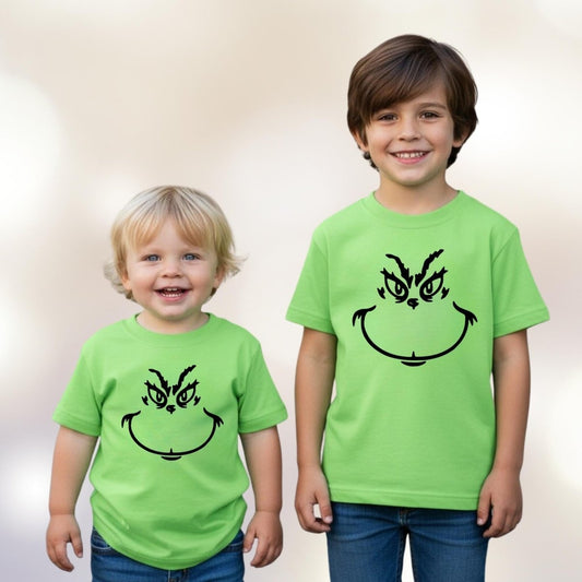 2 boys standing with lime green Grinch face tshirts on standing on white background.
