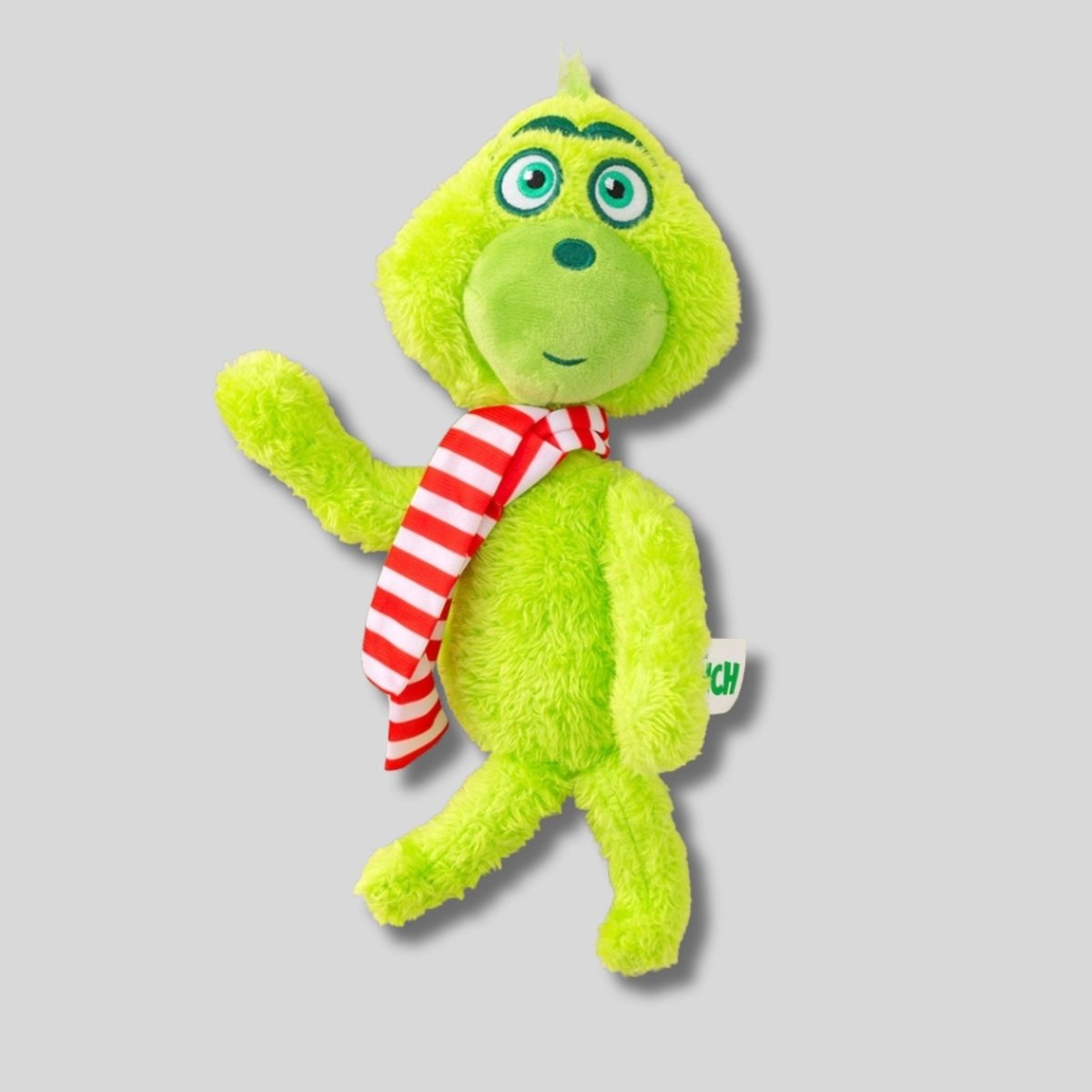 Green Grinch plush toy with a red and white striped scarf on a gray background. Little Gift Nook