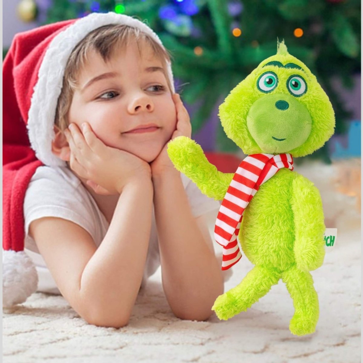 Child wearing a Santa hat with a green Grinch plush toy in front of a Christmas tree. Little Gift Nook