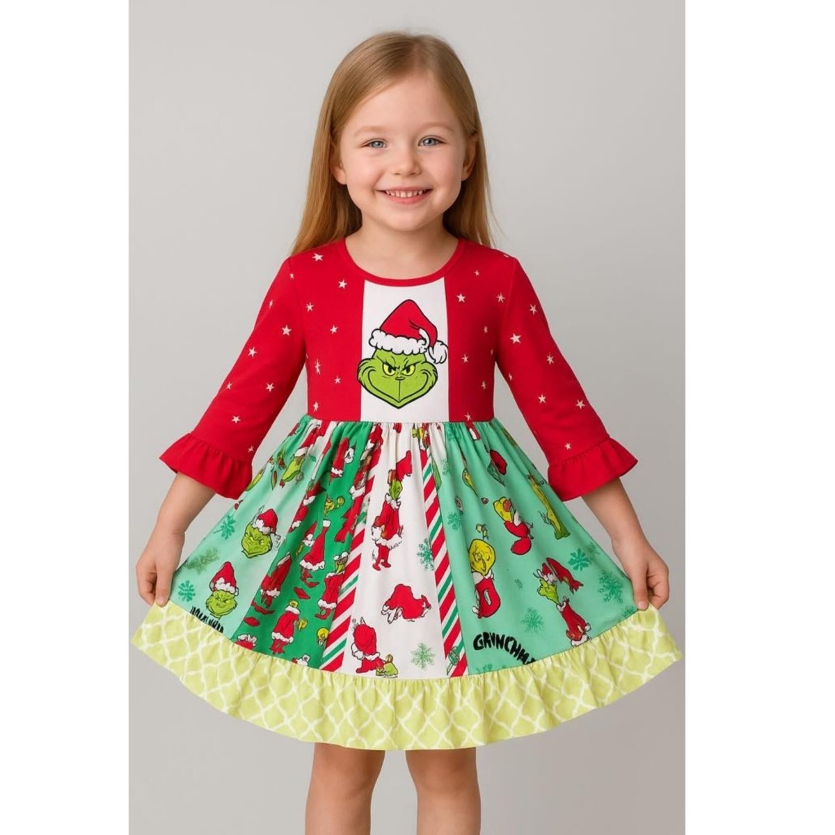 Little girl wearing red and green Grinch theme twirl dress on gray background. 