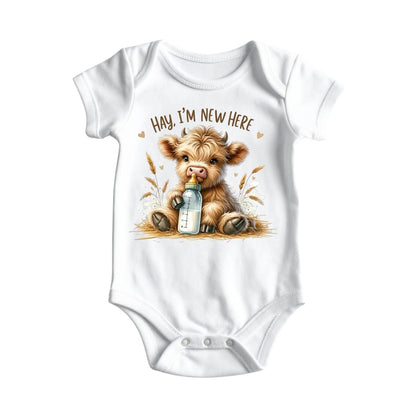 White baby onesie with image of baby highland cow, bottle, and caption "Hay, I'm new here" on front laying on white background. 