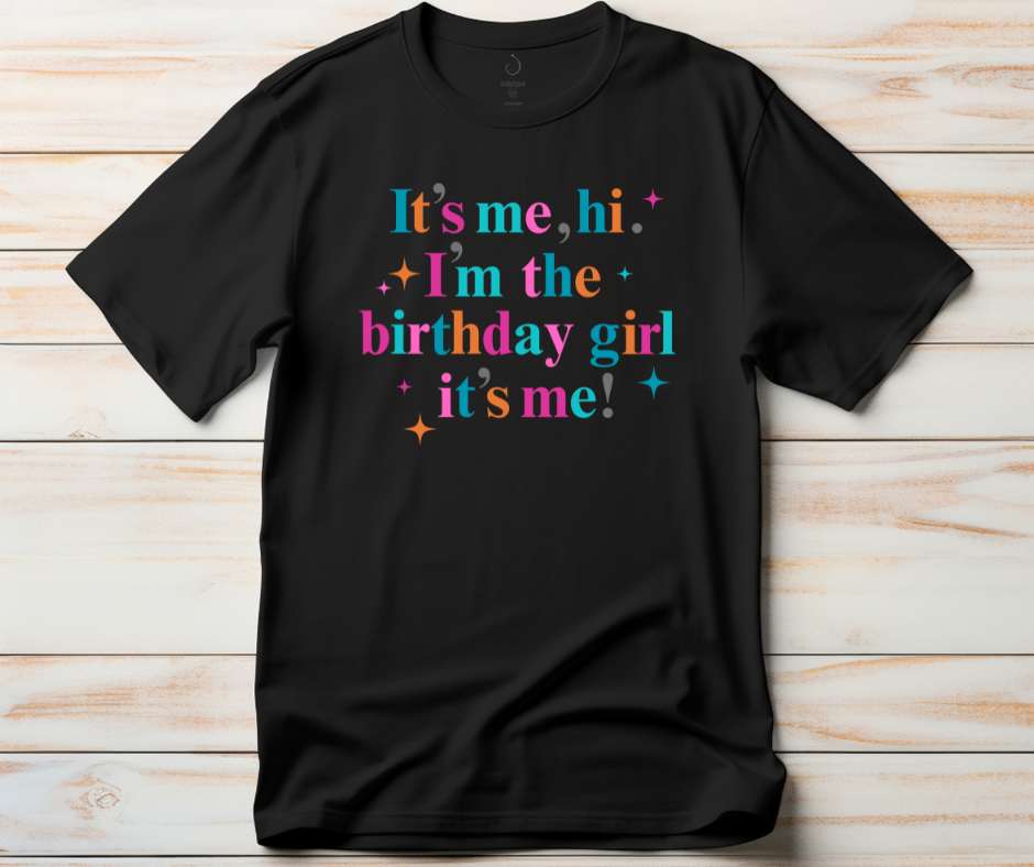 Black t-shirt with colorful text  'It's me, hi, I'm the birthday girl, it's me!' with stars image. 
