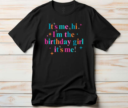 Black t-shirt with colorful text  'It's me, hi, I'm the birthday girl, it's me!' with stars image. 
