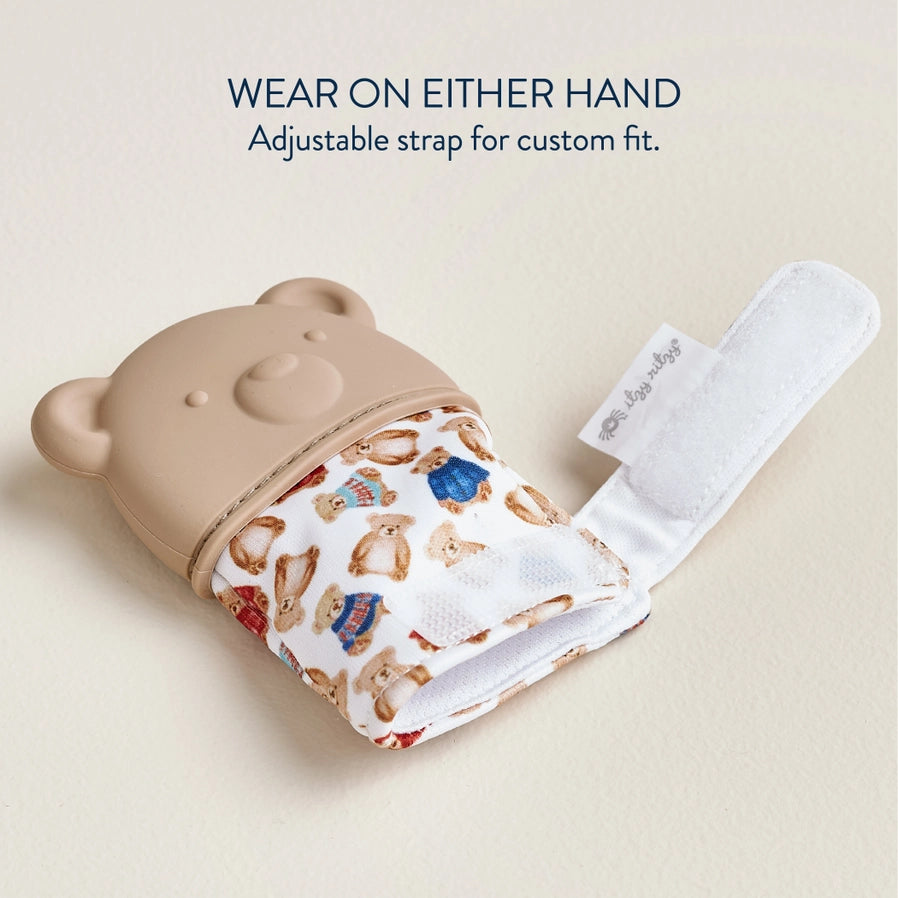 Itzy Ritzy bear teething mitt glove open with velcro closure on a tan background.