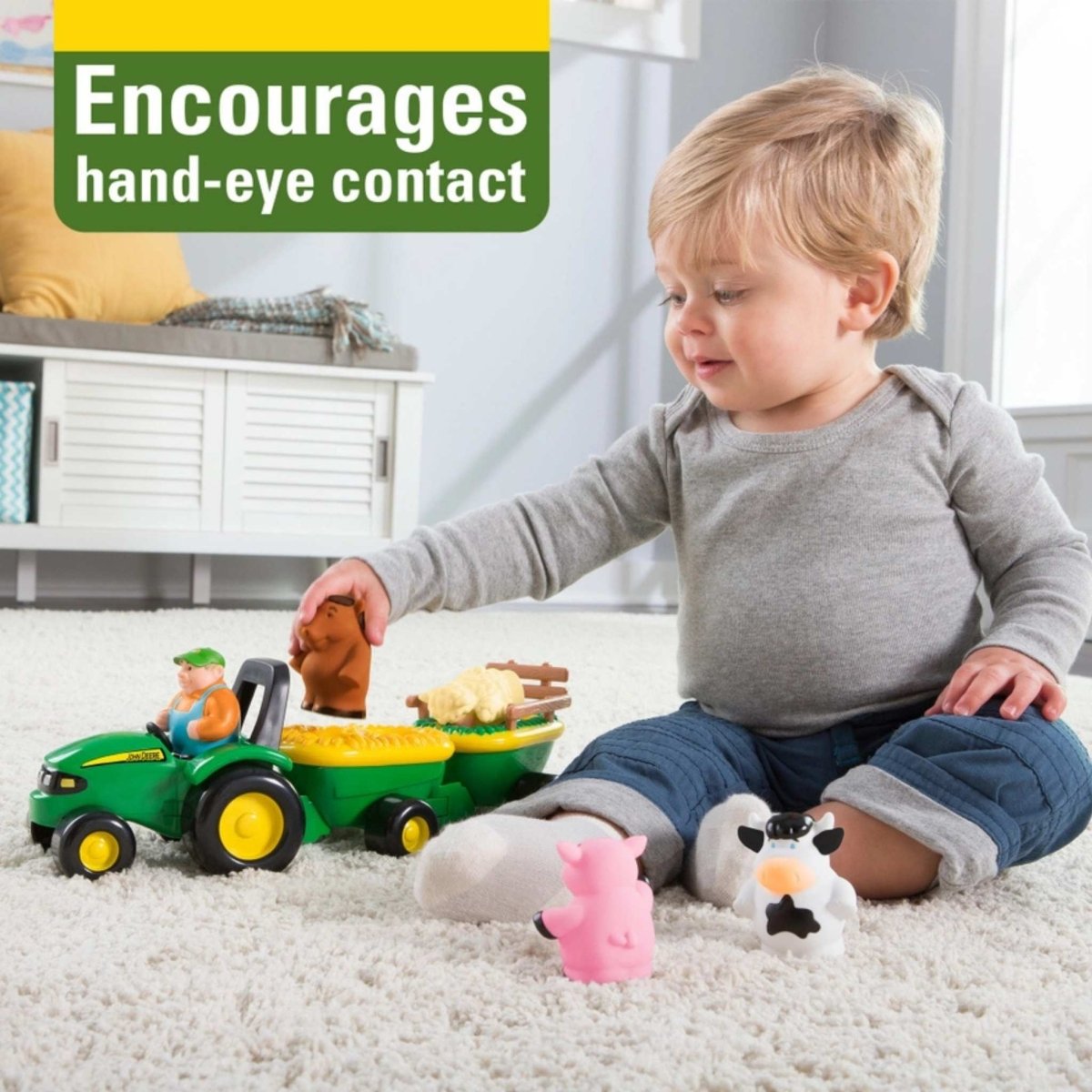 child playing with John Deere Animal sounds musical hayride tractor toy on white carpet. 