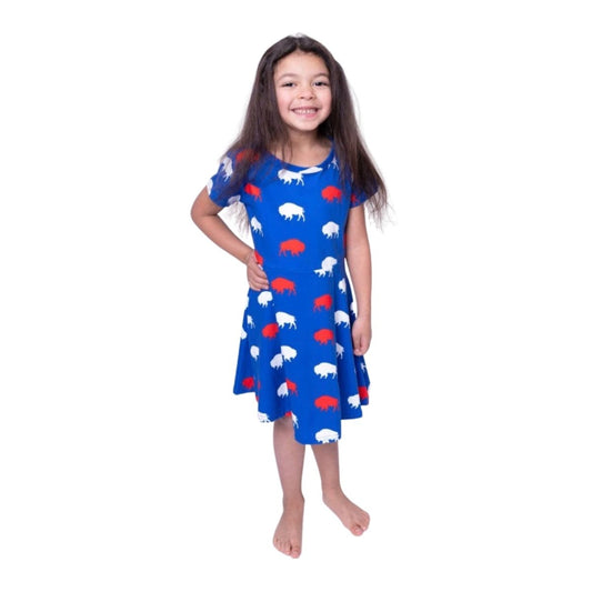 Young girl wearing a blue dress with red and white buffalos print on a white background.