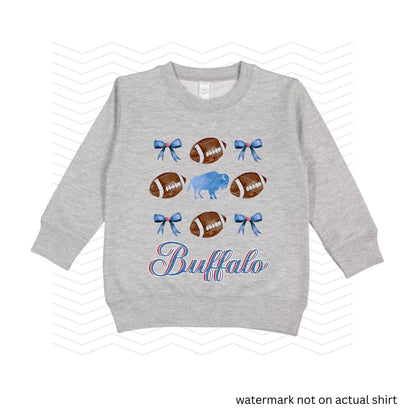 heather gray sweatshirt with blue bows, buffalo, and brown footballs with the text 'Buffalo" in blue and red cursive below image on front.