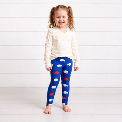 Child wearing royal blue, white, and red buffalo silhouette print leggings and creme top on a white background.