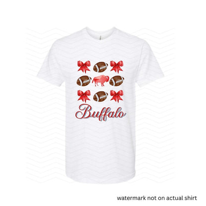 white tshirt with red bows, buffalo, and brown footballs with the text Buffalo in cursive red below image on front.