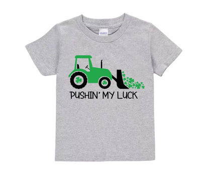Gray kids tshirt with green tractor, clovers, and pushing my luck on front sitting on white background.