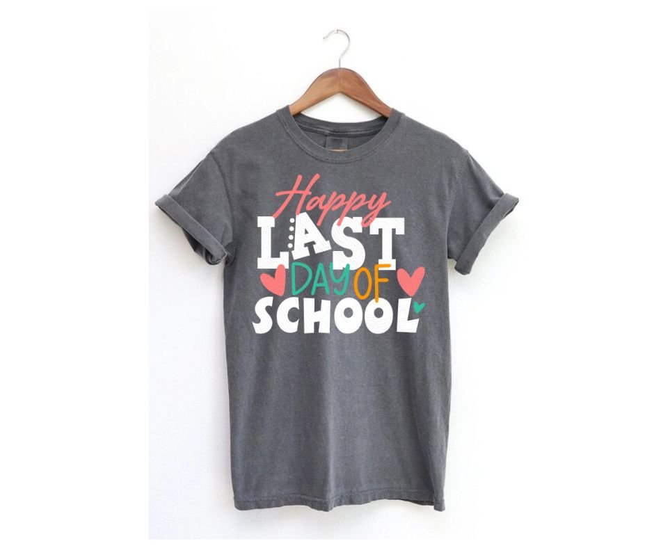 Gray tshirt with pink, white, and green Last Day of School on front on a hanger on a white background. Little Gift Nook