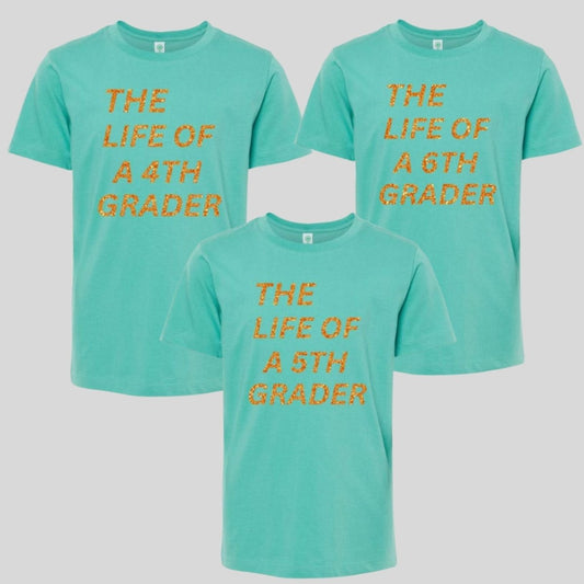 Youth seafoam green orange glitter "The Life of a 4th Grader" "The Life of a 5th Grader" "The Life of a 6th Grader" Tshirts on a white background. Little Gift Nook