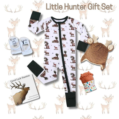 Baby hunter gift set bundle with deer sleeper, knit buck hat, cow teether, take me hunting baby socks, and Good Luck Hunters baby board book on a deer antler print background. Little Gift Nook