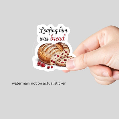 hand holding sticker of "Loafing him was bread heart shapped sourdough loaf with red berries on white background.