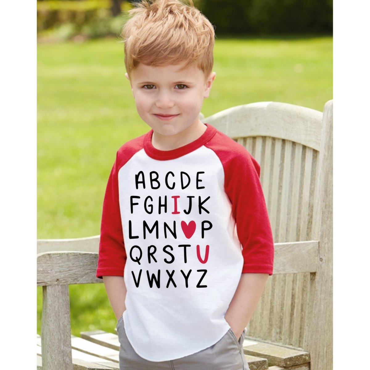 I love you heart colorblock Alphabet Tee. White raglan red sleeve tshirt with alphabet written in black letters with I heart and u in red. Kids tshirt. Tshirt on model of little boy. Little Gift Nook.