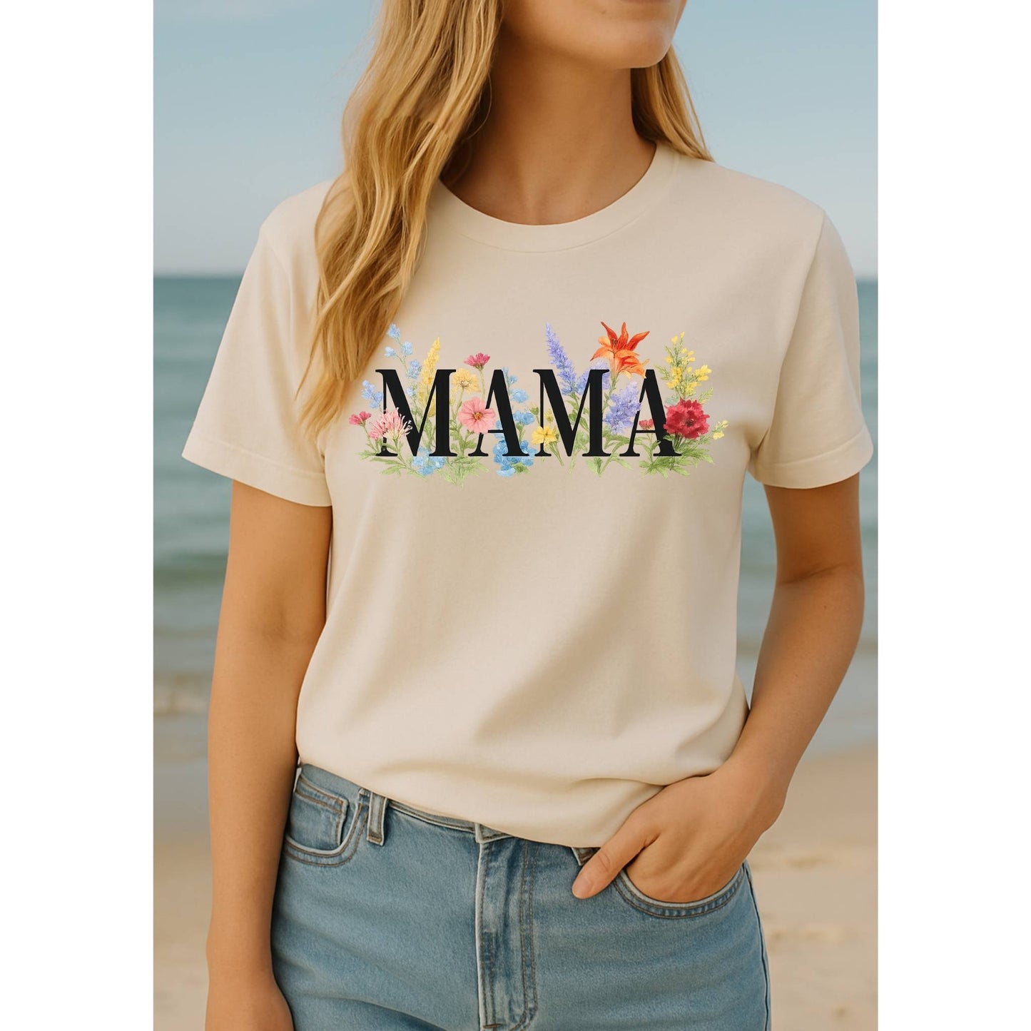 Woman wearing beige floral MAMA tshirt standing in front of ocean.