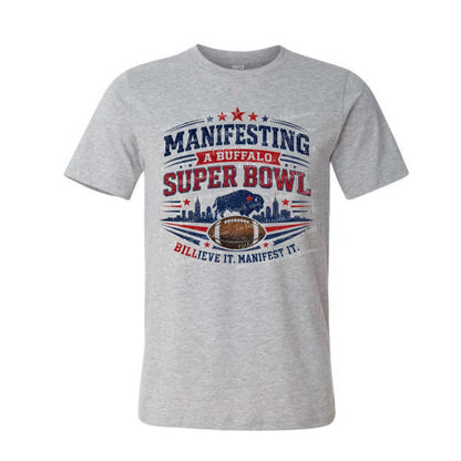 Gray tshirt with red and blue "Manifesting a Buffalo Super Bowl Billieve it manifest it" design on front on a white background.