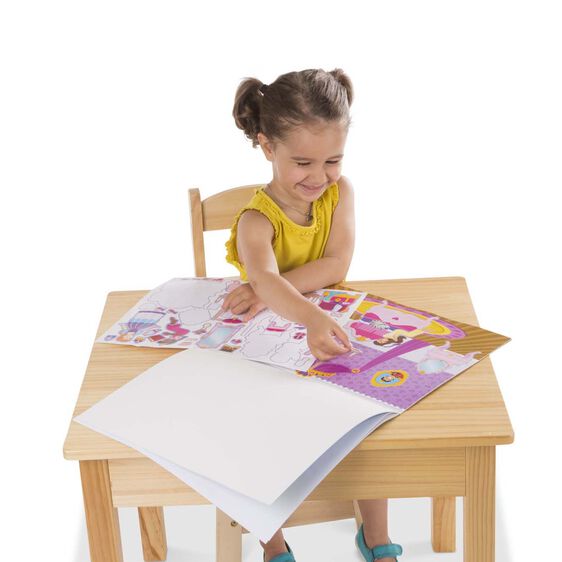 Little girl playing with Melissa & Doug reusable Princess Castle Stickers on wooden desk sitting on white background.