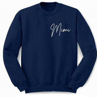Navy crewneck sweatshirt with "Mimi" in white lettering on left chest sitting on white background. Little Gift Nook