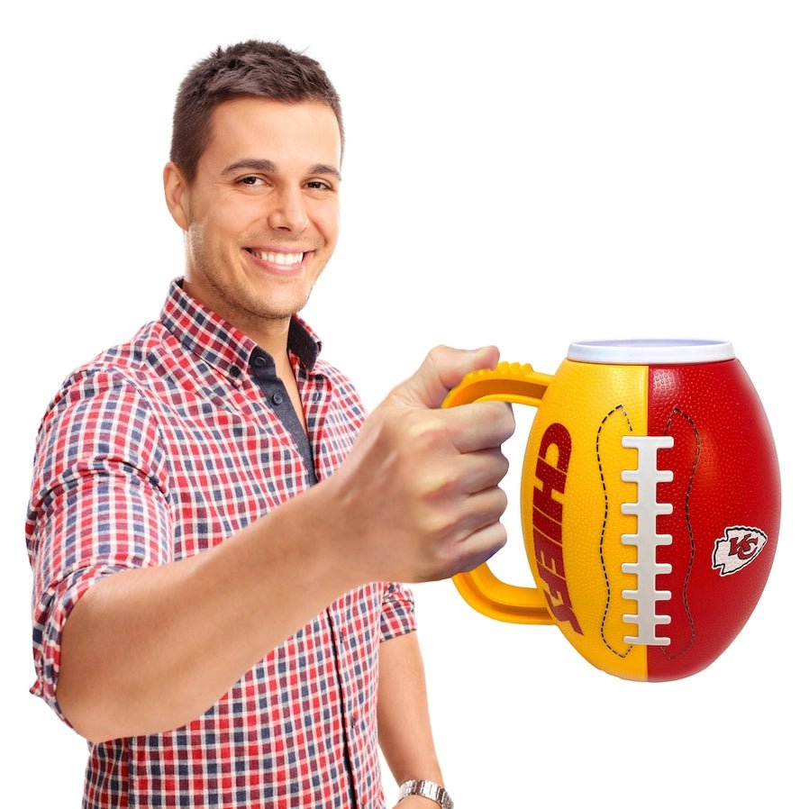 Man holding NFL Kansas City Chiefs plastic 24oz football shaped  Mug with Chiefs logo standing on white background.