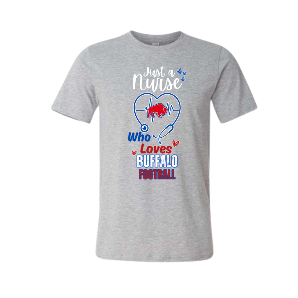 A heather gray short-sleeve crewneck t-shirt featuring a graphic design on the front. The design includes a blue stethoscope forming a heart shape around a red buffalo silhouette, with the text 'Just a Nurse Who Loves BUFFALO FOOTBALL' in white, blue, and red lettering.