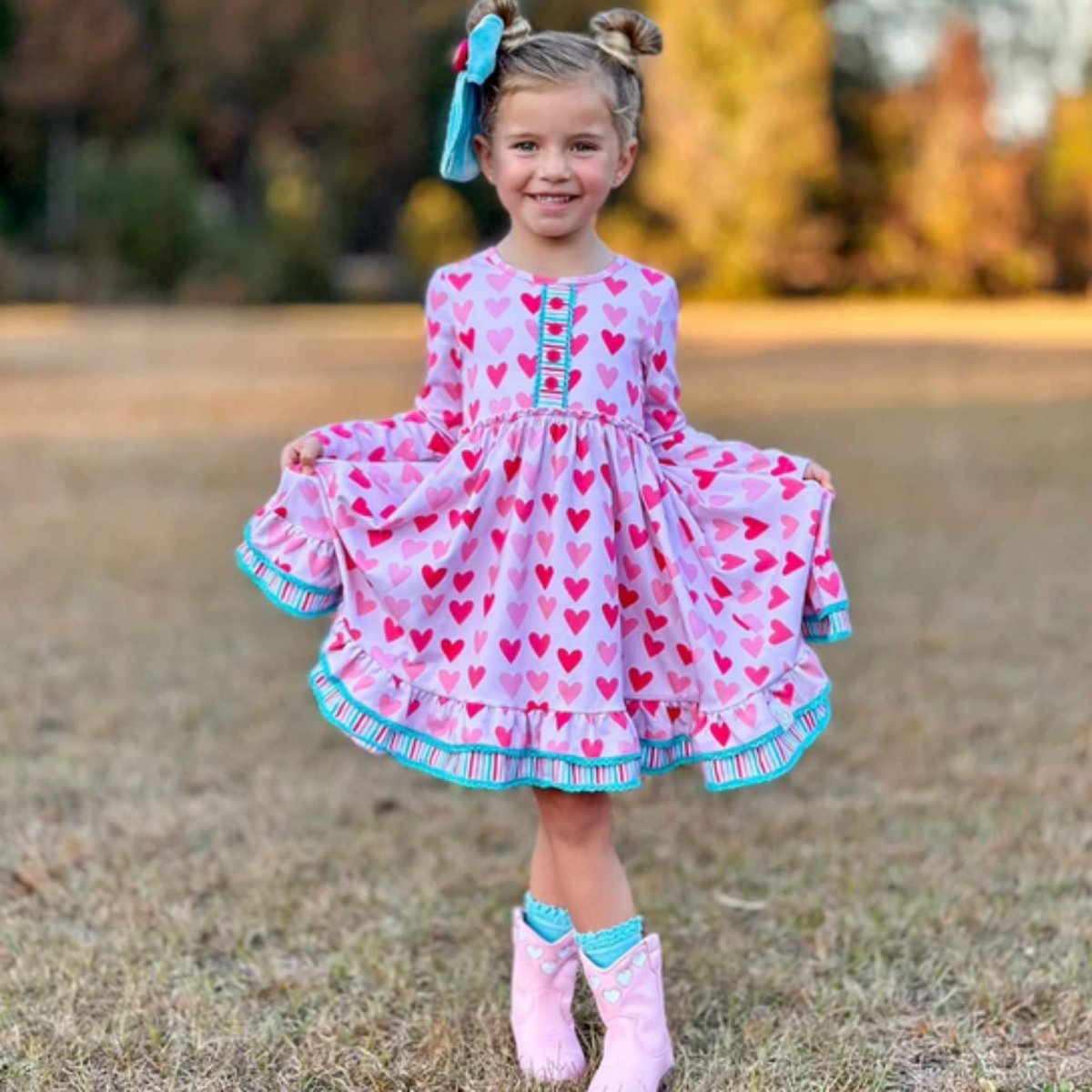 Pink Blue Hearts Ruffle Twirl Dress. Little girl in dress with cute matching hair bow on and pink cowgirl boots. Cotton/Spandex blend 2 pink heart print dress with blue striped accents & ruffle hem.  Pull on/ off.  Buttery soft & Stretchy.  Little Gift Nook.